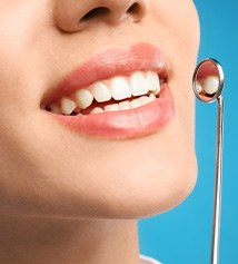 Nose to neck view of woman smiling with dental mirror held up