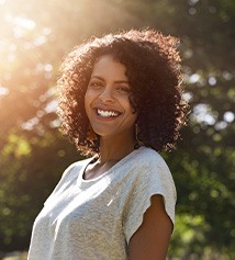 Woman smiling outside in front of large tree