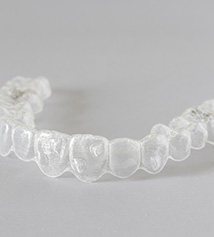 Teenager smiling while holding clear aligner