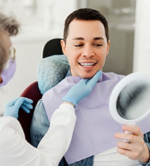 Man smiling at reflection in mirror with dentist