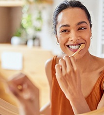 Woman smiling while brushing her teeth