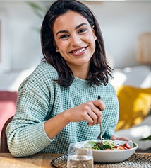 Woman smiling while eating lunch at home