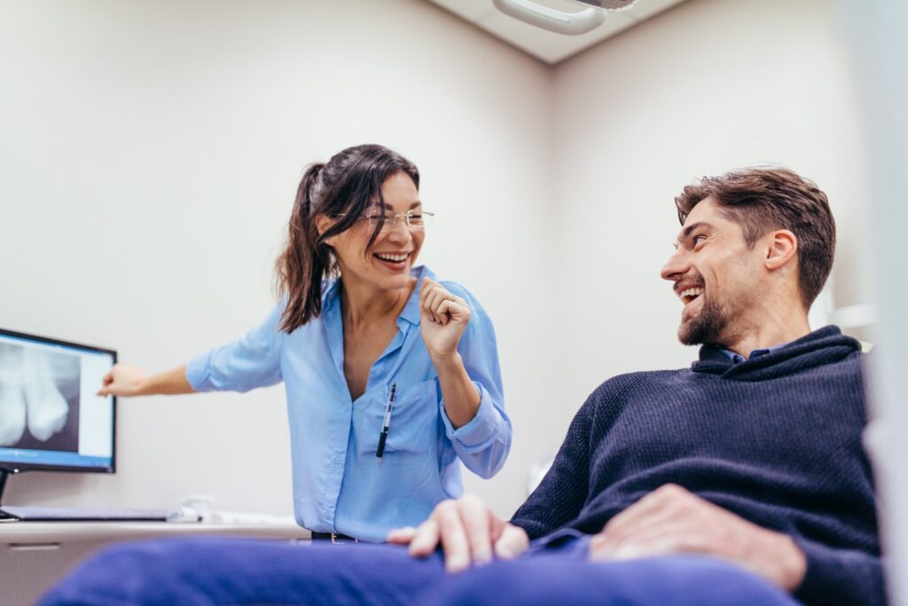 Dentist and patient smiling at each other during consultation